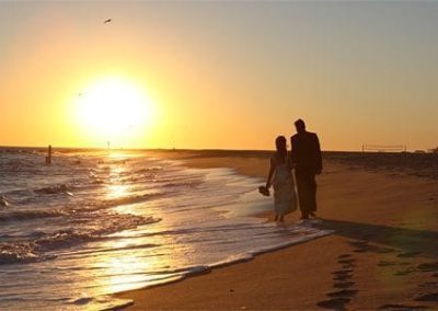 Guest Photos- Couple holding hands and walking next to the beach.